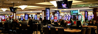 People playing slot machines in a brightly lit casino.