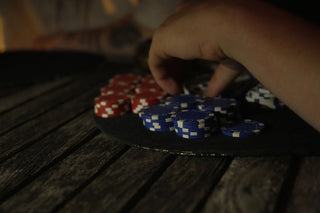 Hand grabbing blue and red poker chips on a table.