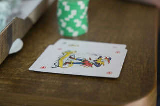 Playing cards, including a joker, on a wooden table.